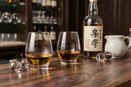 Dégustation de whisky japonais avec trois verres et une bouteille sur un comptoir en bois de noyer dans un bar intime