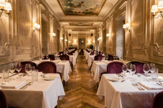 Intérieur élégant d'un grand restaurant étoilé parisien avec nappes blanches, argenterie et décor raffiné